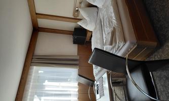 A simple room with a double bed and two chairs. The room has large windows and warm wood decor.