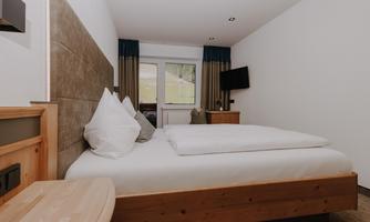 A modern Double Room Basic with a double bed and white pillows.