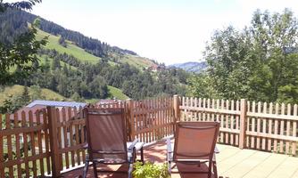 A relaxing balcony with two lounge chairs. In the background, green hills and a blue sky can be seen.