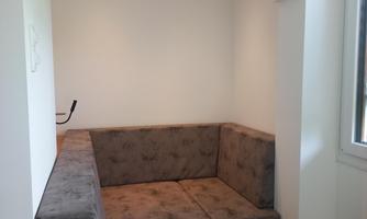 A cozy seating area with gray upholstery and an elegant, arched entrance. The room is bright and designed in a minimalist style.