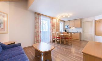 A bright living-sleeping area with a double couch as a sofa bed and a cozy dining area with a table and chairs. The large windows provide bright rooms and a cozy atmosphere. You access the balcony directly, which offers a view of the mountains.