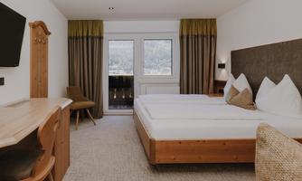 A modern Double Room Comfort with a double bed and a wooden desk.