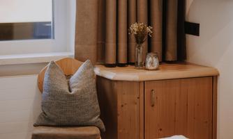 A cosy chair with a cushion stands next to a wooden table.