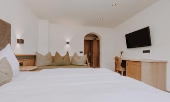 A modern room with two beds and a cosy sitting area.