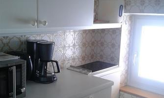 A bright kitchen with white cabinets and a window. On the countertop, there is a coffee machine and a microwave.