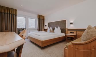 A cosy Double Room Comfort with a large bed and wooden furniture.