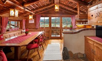 Alpine charm with heart – coziness to arrive and feel at home. Step into our lovingly furnished cabin and feel immediately: This is a temporary home. In our rustic parlor with traditional wooden furniture, red heart décor, and warm light, you will experience true Alpine coziness. Whether at breakfast at the large wooden table, reading on the comfortable corner sofa, or playing with the family – this room invites you to linger. Red cushions, traditional checkered curtains, and handcrafted details create a cozy atmosphere, like the one found only in a real alpine hut. A place to unwind, enjoy, and connect – exactly what makes a real cabin holiday.