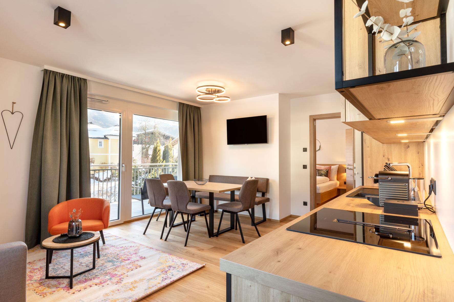 A modern room with an open kitchen and dining area.  
Large windows provide plenty of light and a cozy atmosphere.