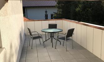 A cozy outdoor area with a table and chairs. From the terrace, you can directly see the surrounding mountains and the garden.