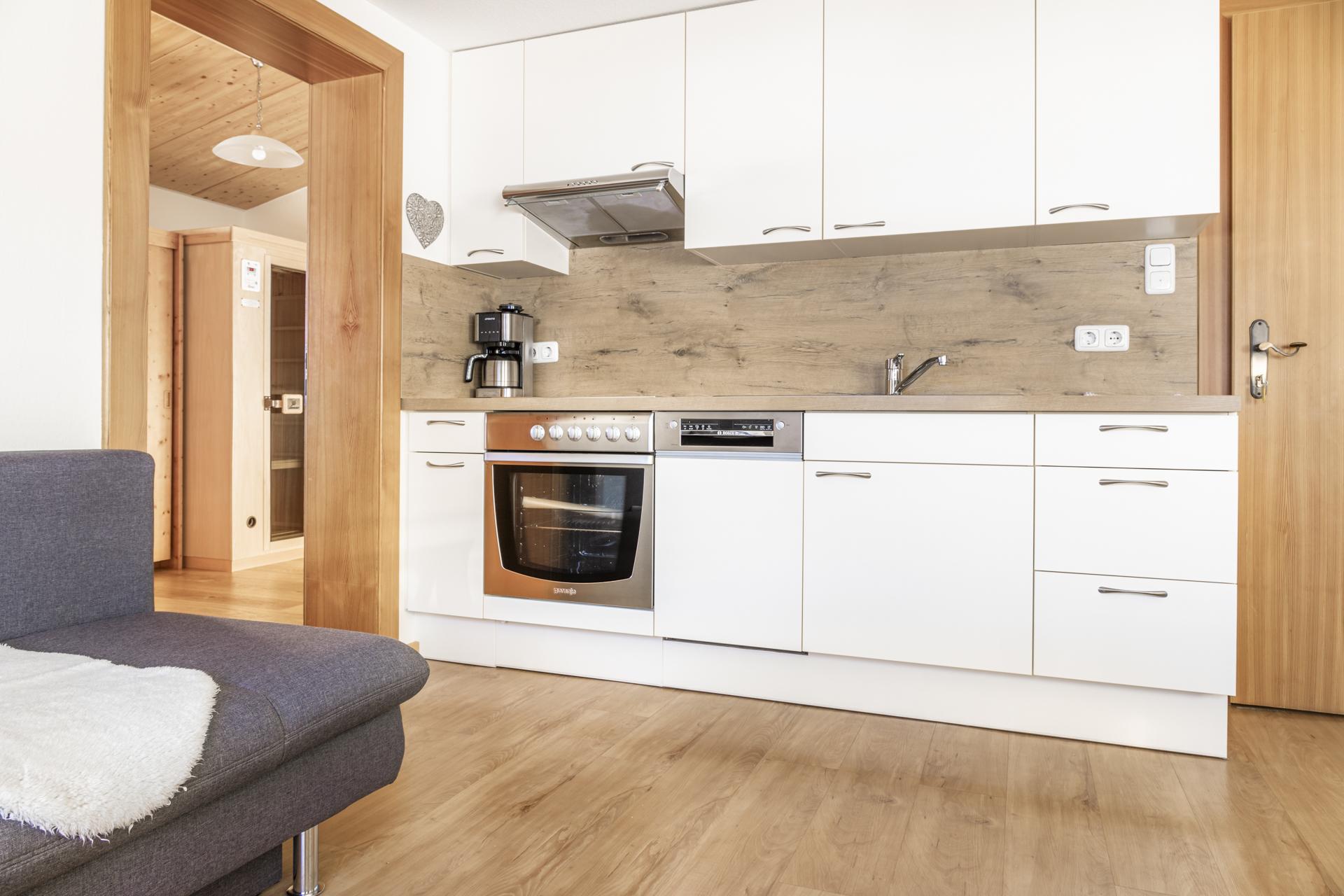 A modern kitchen with white cabinets and a wooden workspace. The space is designed to be bright and welcoming.