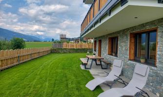 A cozy terrace with loungers and a table in the greenery. In the background, gentle hills and a beautiful view can be seen.