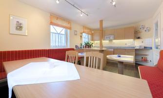 In the lounge on the ground floor, families of the apartments can meet and spend cozy evenings together. The room is equipped with tables, a bench, and chairs.