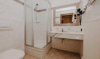 A modern bathroom with a glass shower cabin and a white sink.