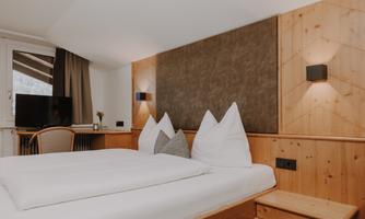 A cosy Double Room Attic with a double bed and wooden paneling.