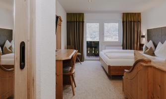 A cosy Double Room Comfort with two beds, sofa bed and wooden furniture.