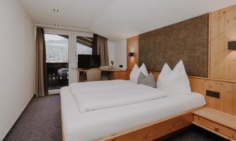 A cosy Double Room Attic with a double bed and wooden details.