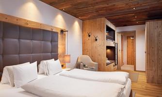 Family-friendly bedroom with double and bunk beds. This stylish bedroom accommodates the whole family: a cozy double bed and two integrated bunk beds with high-quality wooden finishes ensure comfort and privacy at the same time. The warm lighting, natural materials, and loving details create an inviting atmosphere. Perfect for relaxing nights after an eventful day in the mountains.