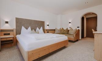 A modern Double Room Comfort with a large bed, wooden furniture, and cosy pillows.