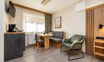 A modern apartment with a dining area and a cozy seating corner. There is a television and a well-equipped kitchenette.