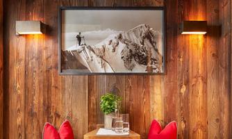 Cozy retreat with alpine flair! This lovingly designed getaway invites you to linger: Warm wood paneling, atmospheric lighting, and a comfortable bench with soft cushions create an atmosphere full of comfort. The historical mountaineer photo on the wall underscores the alpine character of the room. An ideal spot for reading, relaxing, or simply taking a break – perfect after a sauna session or an active day in the mountains.