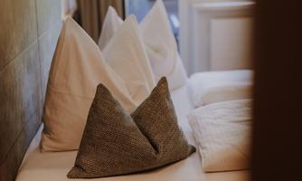 A cozy bed with several pillows in different colors.