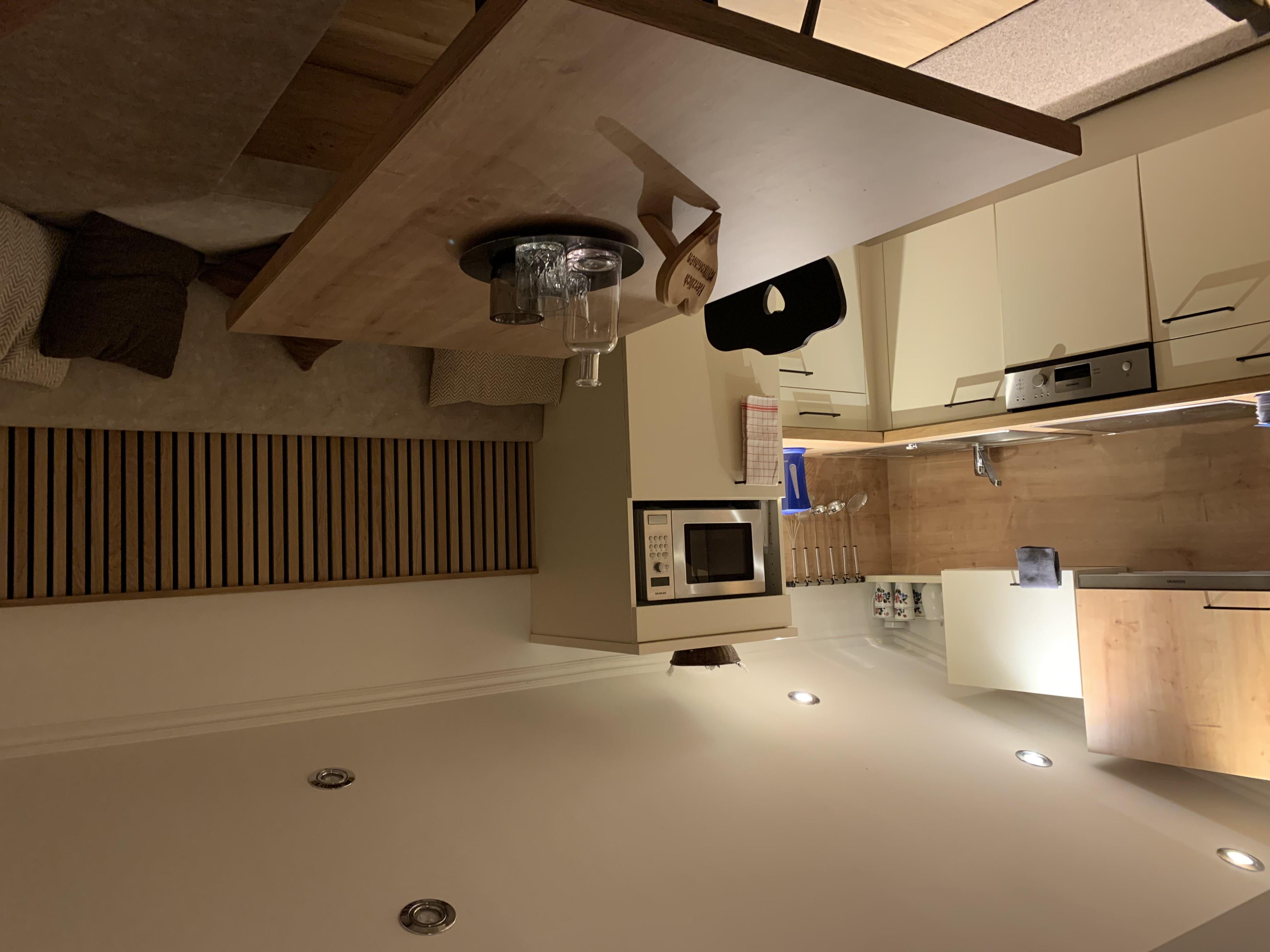 A modern kitchen with wooden surfaces and a cozy seating area. The kitchen is fully equipped with a dishwasher, microwave, stove, coffee maker, etc.