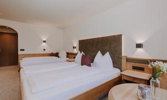 A cosy room with a double bed, a single bed, a sofa bed, and modern wooden furniture.