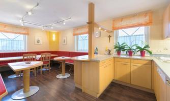 In the lounge on the ground floor, families of the apartments can meet and spend cozy evenings together. The room is equipped with tables, a bench, and chairs.