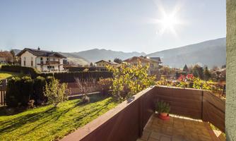 A beautiful view from a balcony over green meadows and mountains. The sun shines bright in the sky.