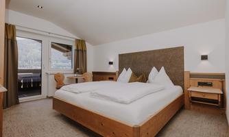A modern Double Room Comfort with a large double bed and wooden furniture.