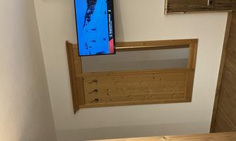 A cozy room with wooden paneling. A television hangs on the wall.