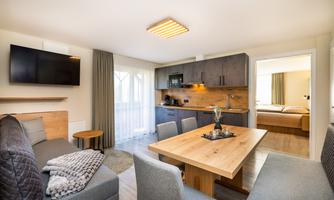 A modern living-sleeping area with a comfortable seating arrangement and a dining table. The kitchen is well-equipped, and the light is bright and inviting.
