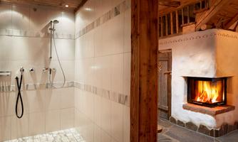 Refreshing Kneipp shower meets cozy warmth. A place to breathe: The spacious, ground-level shower with Kneipp hose offers refreshment and soothing cooling – ideal after a sauna session or an active day in the mountains. The elegant natural tiles, combined with rustic wooden elements and stylish lighting, create a harmonious feel-good atmosphere. Adjacent to it, the cozy fireplace area with crackling fire invites relaxation – a perfect connection of wellness and alpine charm.