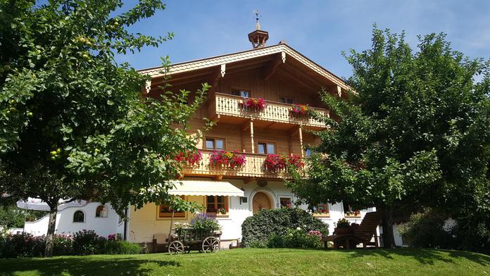 A charming wooden house with balconies, adorned with blooming flowers. Surrounded by lush greenery and trees.