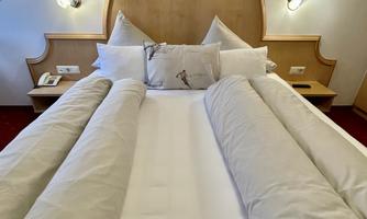 A cozy bedroom with a large bed and soft pillows. The walls are painted in warm tones and there are decorative lights.