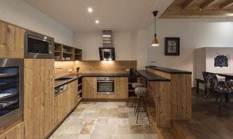 A modern kitchen with wooden cabinets and stylish appliances. The space is bright and inviting with a cozy bar area.