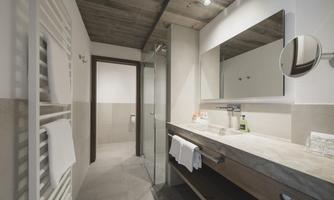 A modern bathroom with a glass shower, a large mirror, and stylish fixtures. The walls are bright and minimally decorated.