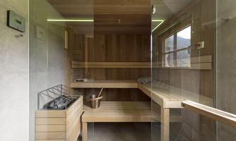 A modern sauna with wooden benches and glass walls. It is bright and inviting, perfect for relaxation.