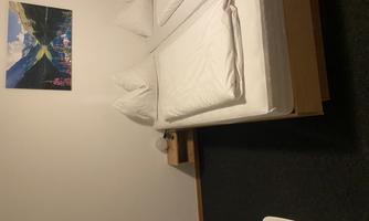 A simple room with two beds and fresh bed linen. A landscape picture hangs on the wall.