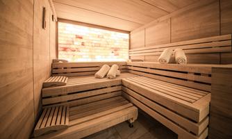 A bright sauna with a wooden bench and fresh towels. The warm atmosphere invites relaxation.
