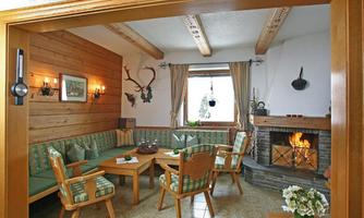 A cozy living space with wooden walls, a fireplace, and an inviting seating area. The decor is rustic and warm, perfect for relaxing evenings.