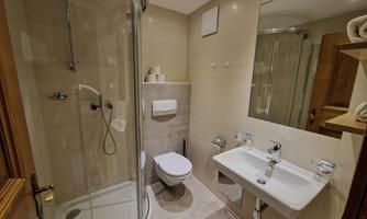 A modern bathroom with a glass shower and a sink. The walls are brightly tiled, and there is a large mirror.