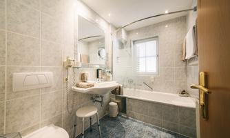 A modern bathroom with tiles in neutral colors. There is a bathtub, a sink, and a large mirror.