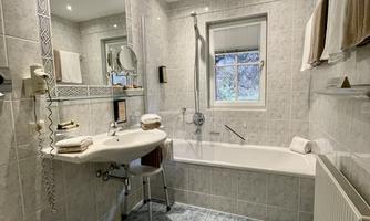 A modern bathroom with a bathtub and a shower. There are bright tiles and a large mirror.