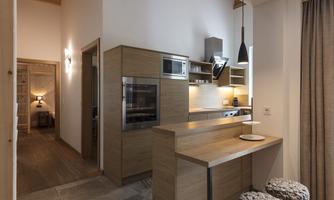 A modern kitchen with wooden cabinets and a elegantly designed bar. The space is bright and inviting, with stylish light fixtures.