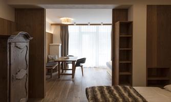 A modern room with wooden furniture and a large window. A table with chairs invites you to linger.