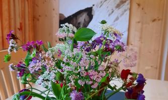 A beautiful bouquet of flowers in a glass vase is on a table. In the background, there is a large picture of a skier.