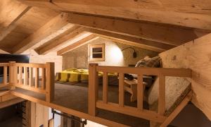 A cozy sleeping area in a wooden house with a balcony and a view of the living room below. The decor is modern and inviting.
