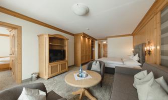 A stylishly furnished room with wooden details and cozy furniture. The room features a sofa, a table, and a television, as well as a window that lets in daylight.