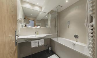 A modern bathroom with a bathtub and a sink. Bright walls and pleasant lighting create a relaxing atmosphere.